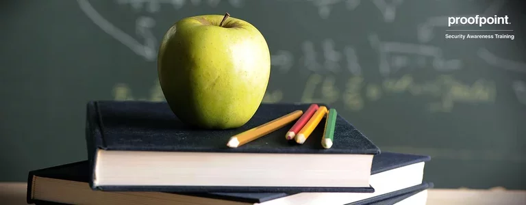 Apple, colored pencils, and books with a blackboard in the background